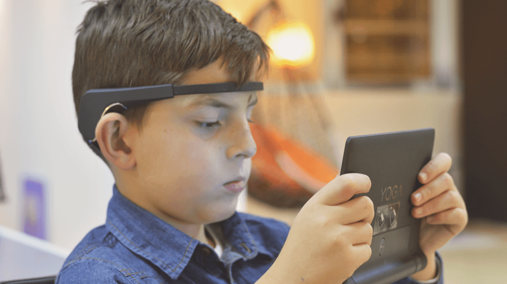 Niño utilizando una banda EEG para neurofeedback mientras interactúa con una tableta durante sesión terapéutica.
